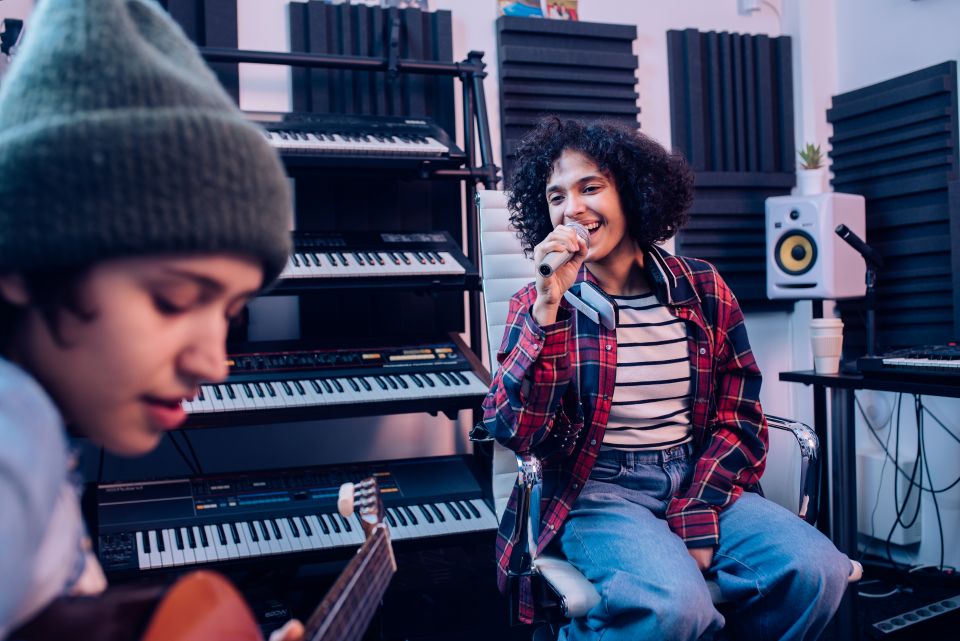 person singing into microphone while another person plays a guitar